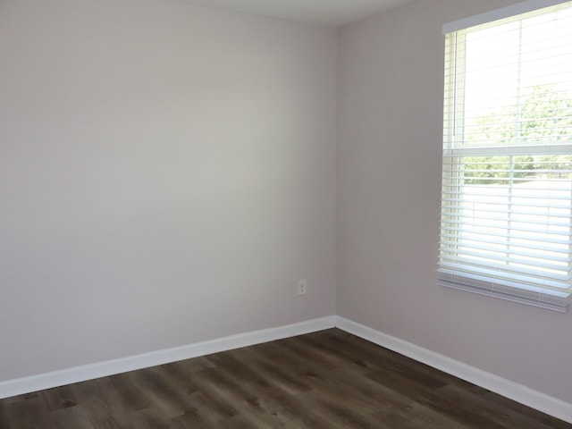 spare room with dark hardwood / wood-style flooring and a wealth of natural light