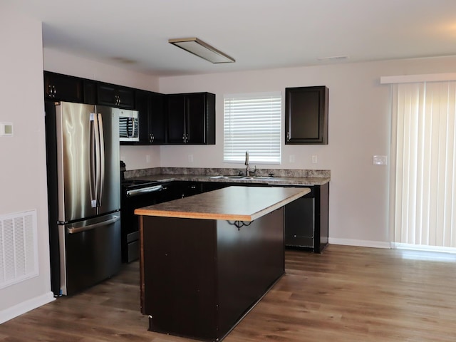 kitchen featuring a center island, sink, black range with electric cooktop, wood-type flooring, and stainless steel refrigerator