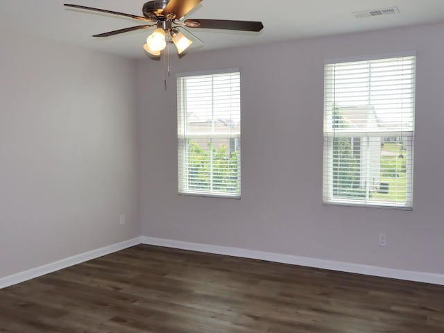 unfurnished room with a wealth of natural light, dark wood-type flooring, and ceiling fan