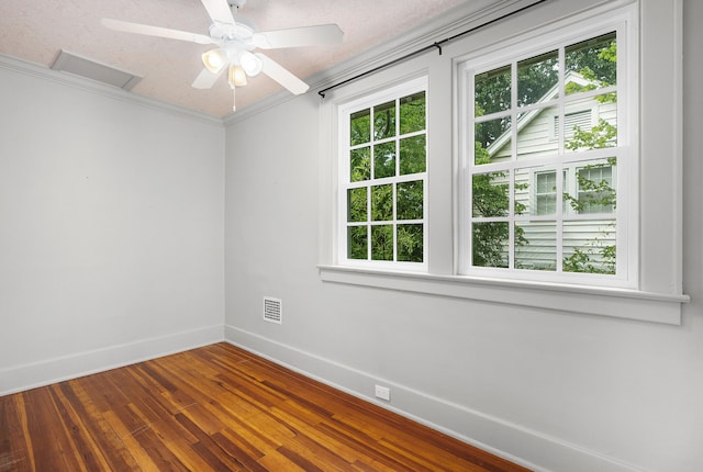 unfurnished room featuring wood-type flooring, a textured ceiling, a wealth of natural light, and ornamental molding