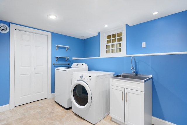 washroom with cabinets, washing machine and dryer, and sink