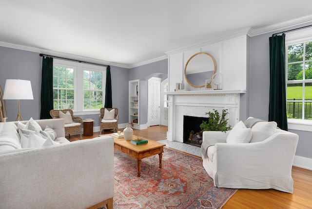 living room with a wealth of natural light, hardwood / wood-style floors, and a brick fireplace