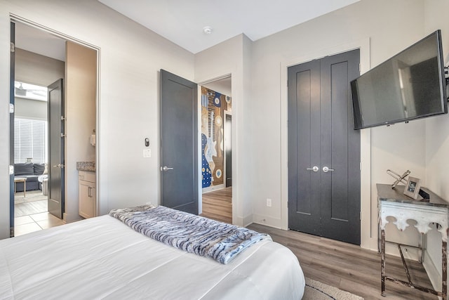 bedroom with a closet, ensuite bathroom, and light hardwood / wood-style flooring