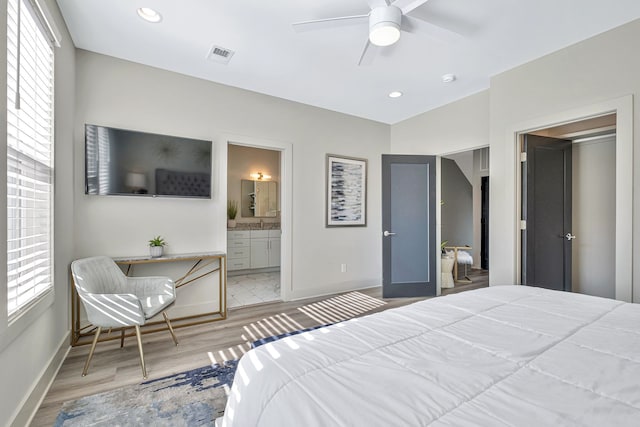 bedroom featuring light hardwood / wood-style flooring, ensuite bath, ceiling fan, and multiple windows