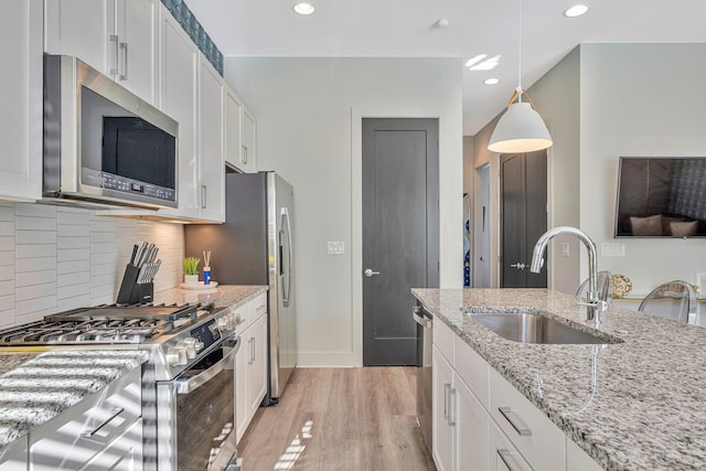 kitchen with light hardwood / wood-style flooring, tasteful backsplash, sink, white cabinetry, and appliances with stainless steel finishes