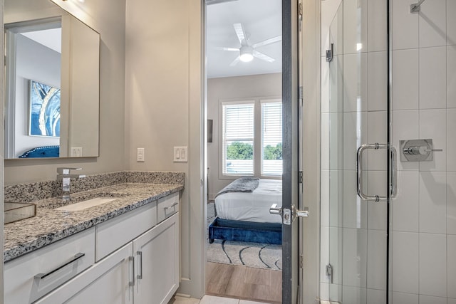 bathroom featuring ceiling fan, vanity with extensive cabinet space, an enclosed shower, and wood-type flooring