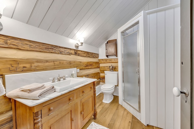 bathroom featuring hardwood / wood-style floors, log walls, lofted ceiling, toilet, and vanity