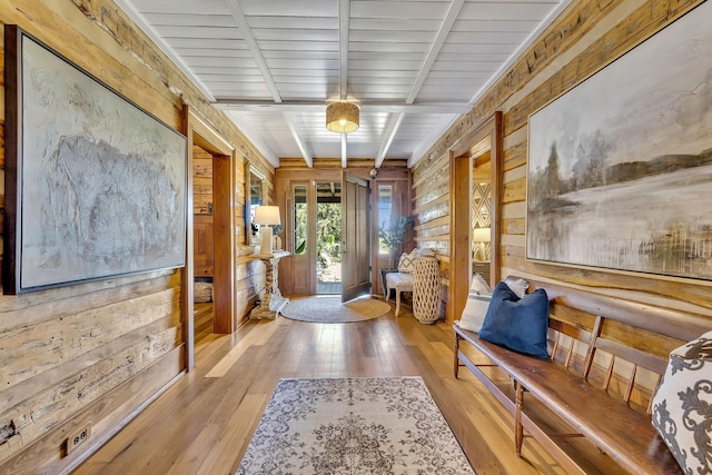 interior space with light wood-type flooring, beam ceiling, and wood walls