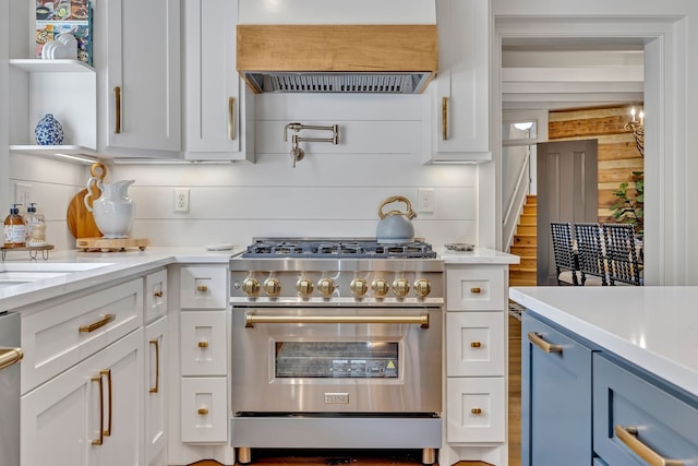 kitchen with custom range hood, blue cabinetry, white cabinetry, and high end stove