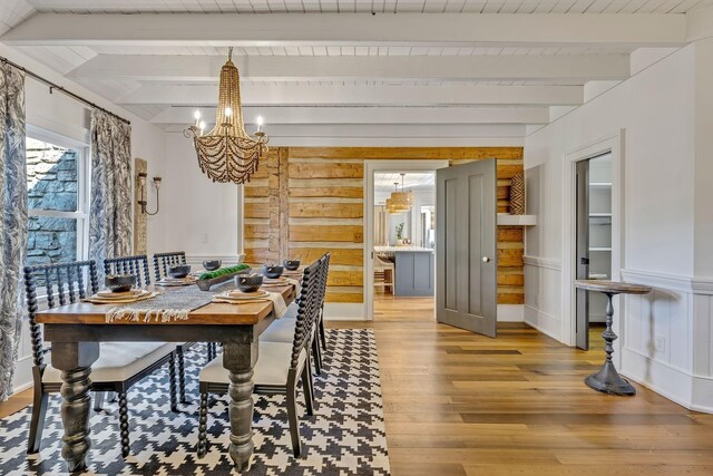 dining area featuring a notable chandelier, beam ceiling, and light wood-type flooring