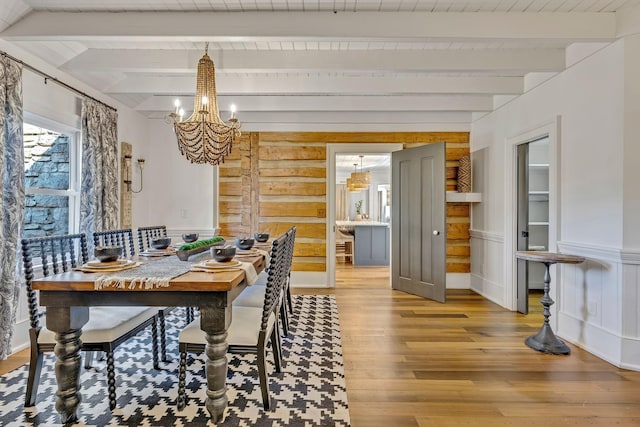 dining area with hardwood / wood-style flooring, wood ceiling, a chandelier, and beam ceiling