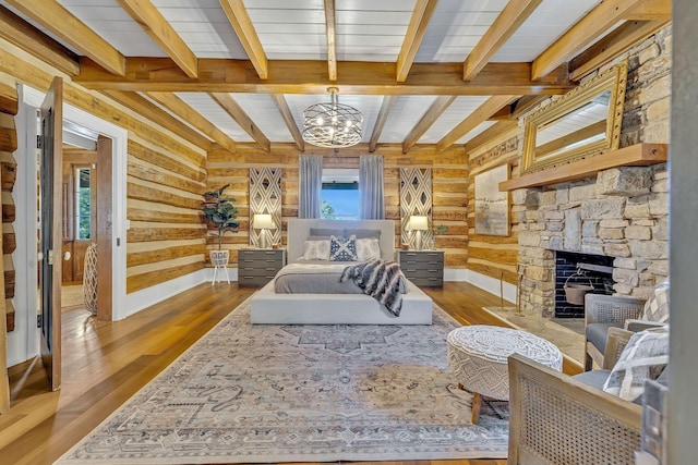 bedroom with hardwood / wood-style flooring, wooden walls, a notable chandelier, and a fireplace