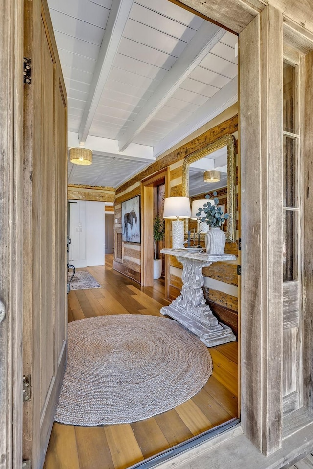 hall with beam ceiling, light hardwood / wood-style floors, and wood walls