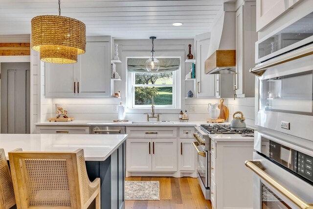 kitchen featuring hanging light fixtures, backsplash, range with gas cooktop, stainless steel oven, and custom exhaust hood