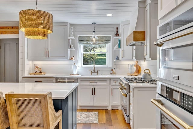 kitchen featuring pendant lighting, white cabinets, high end stainless steel range oven, and premium range hood