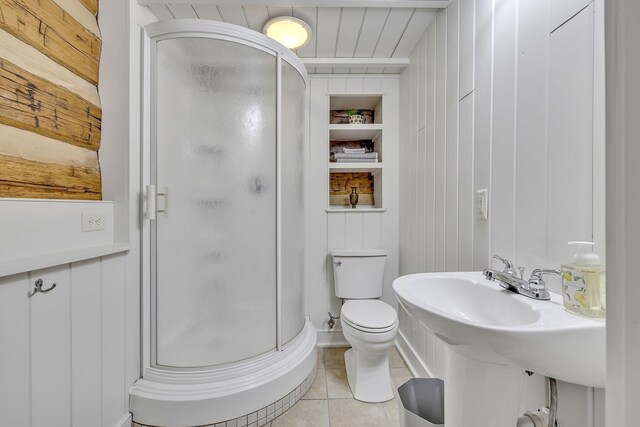 bathroom featuring a shower with shower door, tile flooring, and toilet