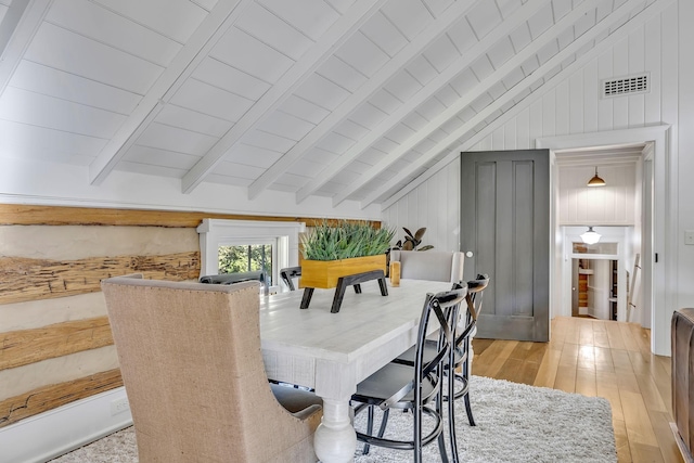 dining area with vaulted ceiling with beams, wood ceiling, light hardwood / wood-style floors, and wood walls