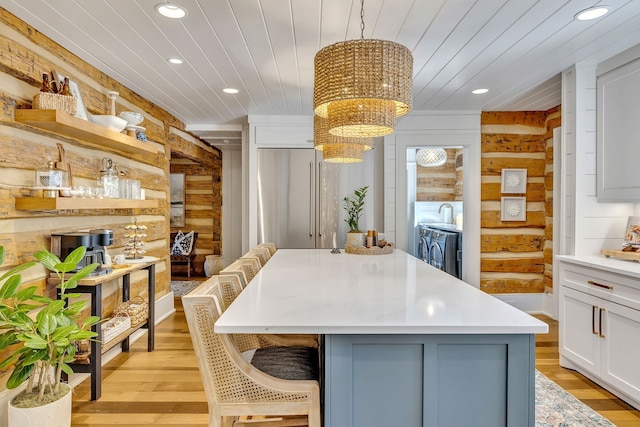 interior space featuring a center island, wooden walls, light wood-type flooring, and pendant lighting