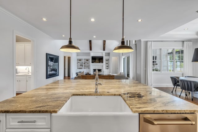 kitchen featuring white cabinetry, light stone countertops, sink, and decorative light fixtures