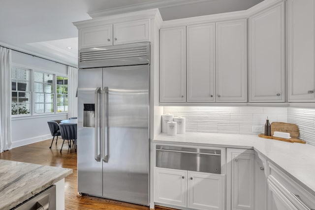 kitchen with backsplash, stainless steel built in fridge, white cabinets, and light hardwood / wood-style floors