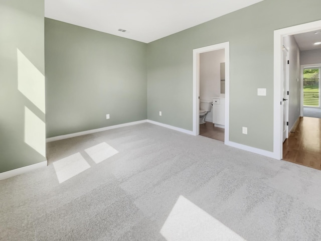 unfurnished bedroom with ensuite bath and light carpet