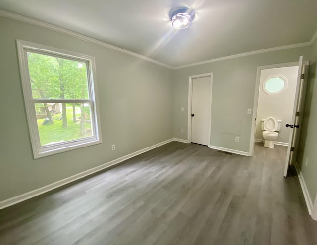 unfurnished bedroom featuring hardwood / wood-style floors, ornamental molding, and connected bathroom