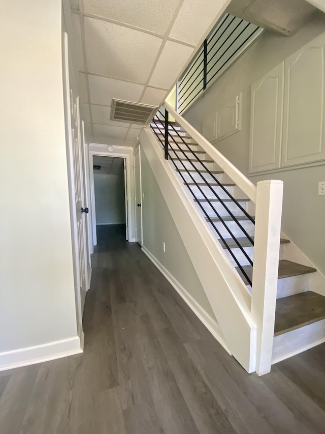 stairway with hardwood / wood-style floors and a drop ceiling