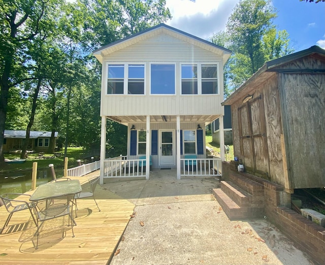 back of house featuring covered porch and a storage unit