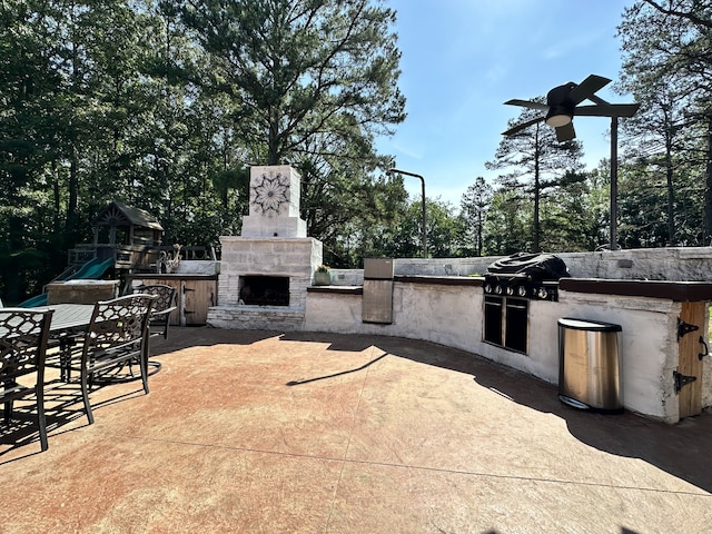 view of patio / terrace with a grill, a playground, an outdoor stone fireplace, and an outdoor kitchen