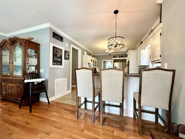 kitchen with light hardwood / wood-style floors, crown molding, decorative light fixtures, and an inviting chandelier