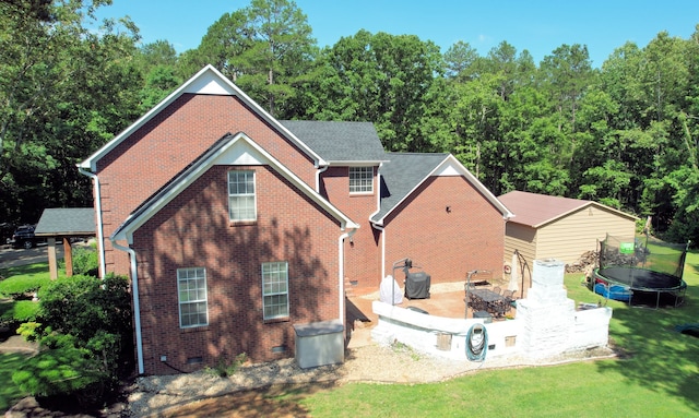 back of house featuring a patio area, a trampoline, and a yard