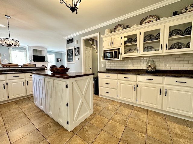 kitchen with a center island, crown molding, tasteful backsplash, and stainless steel microwave