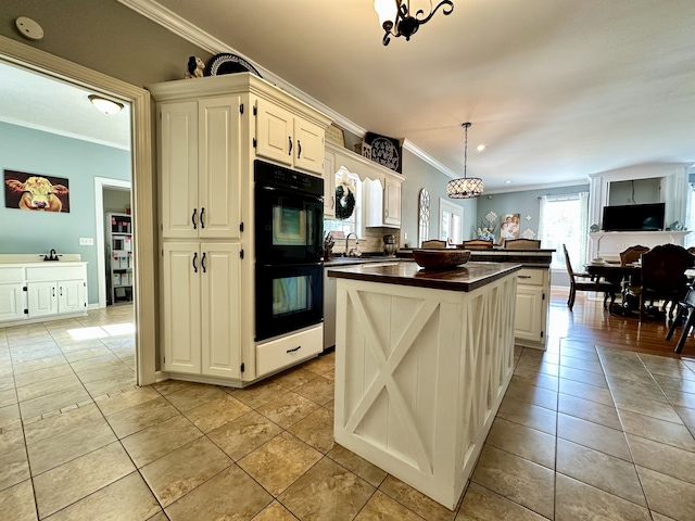 kitchen with double oven, crown molding, a center island, light tile floors, and pendant lighting