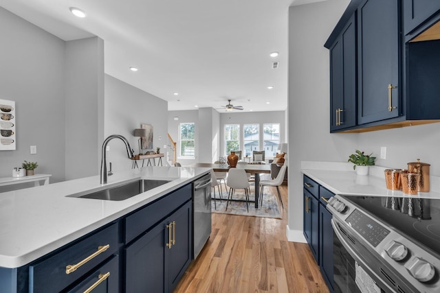 kitchen featuring blue cabinets, sink, light hardwood / wood-style flooring, and stainless steel appliances