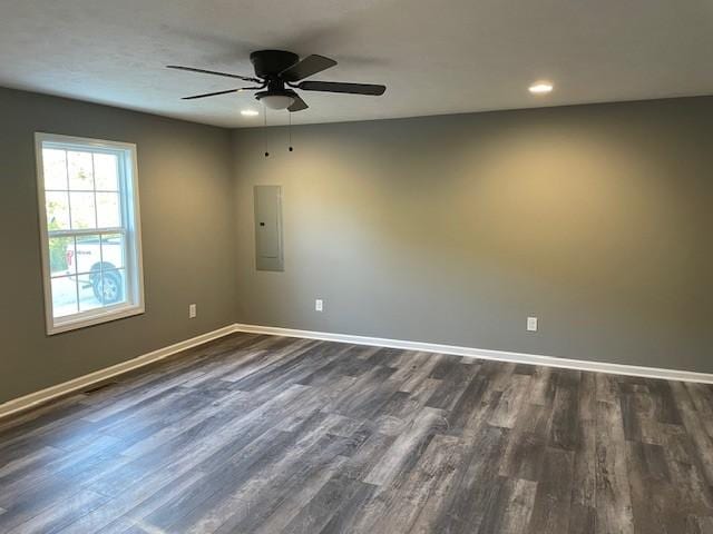 unfurnished room featuring dark wood-style floors, a ceiling fan, electric panel, and baseboards