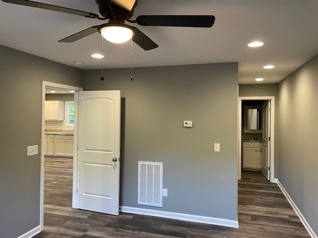 unfurnished bedroom with connected bathroom, dark hardwood / wood-style floors, and ceiling fan