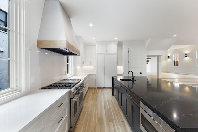 kitchen featuring stainless steel appliances, sink, custom range hood, and white cabinets