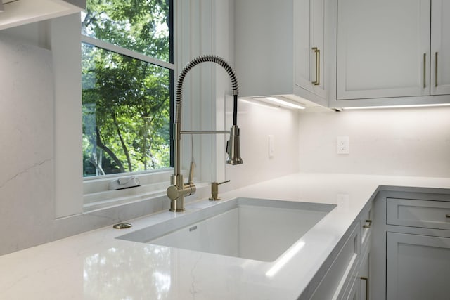 kitchen featuring light stone countertops, sink, and gray cabinetry