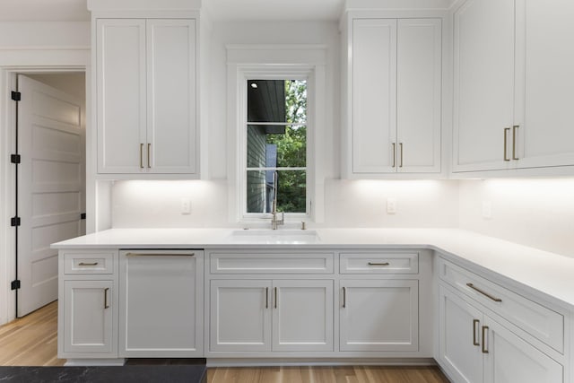 kitchen with white cabinetry, sink, and light wood-type flooring