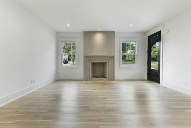 unfurnished living room featuring a large fireplace, plenty of natural light, and light hardwood / wood-style flooring