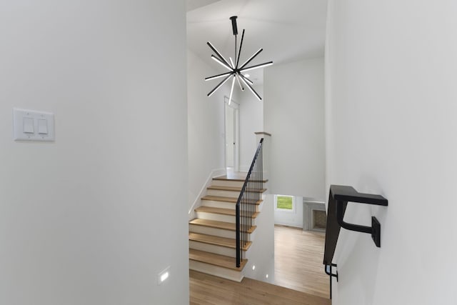 stairs featuring hardwood / wood-style floors and a notable chandelier