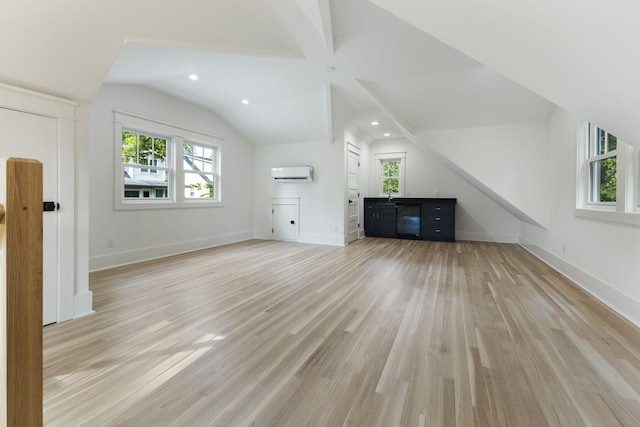 interior space with vaulted ceiling, a wall mounted air conditioner, and light hardwood / wood-style flooring