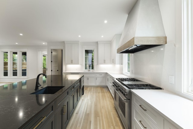 kitchen featuring sink, double oven range, plenty of natural light, custom range hood, and white cabinets