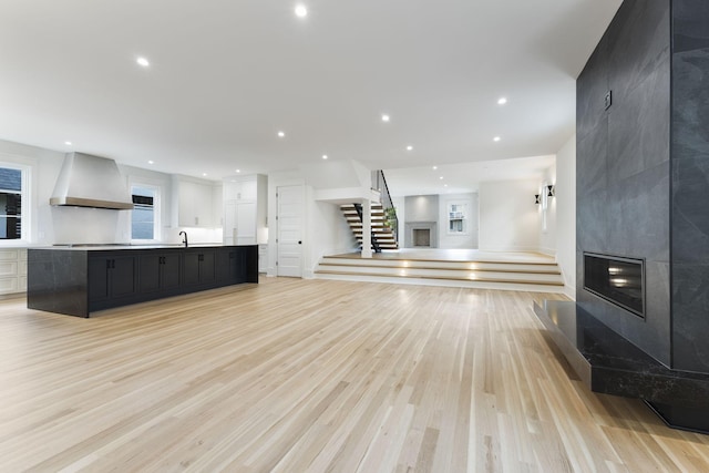 unfurnished living room featuring a fireplace, sink, and light hardwood / wood-style flooring