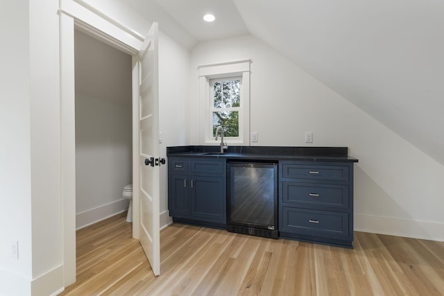 bar featuring lofted ceiling, sink, beverage cooler, and light wood-type flooring