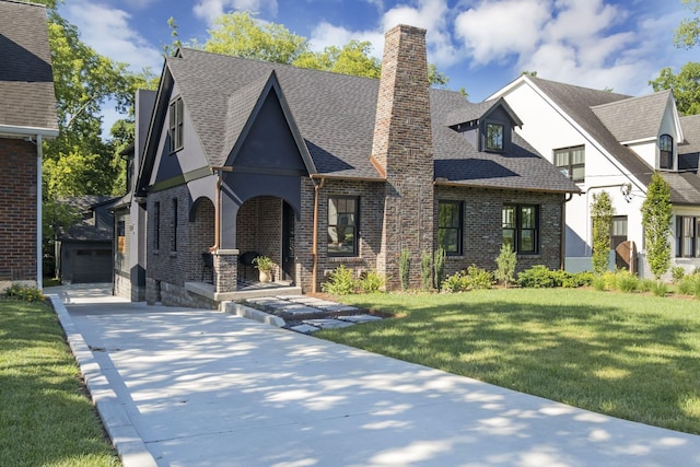 english style home with a garage, an outdoor structure, and a front yard