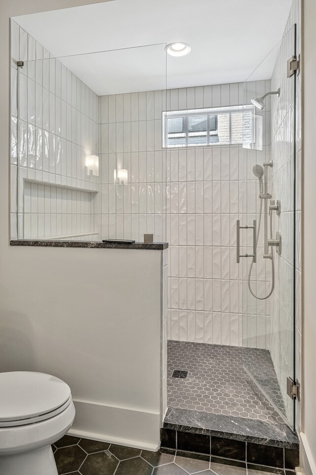 bathroom featuring toilet, an enclosed shower, and tile patterned flooring