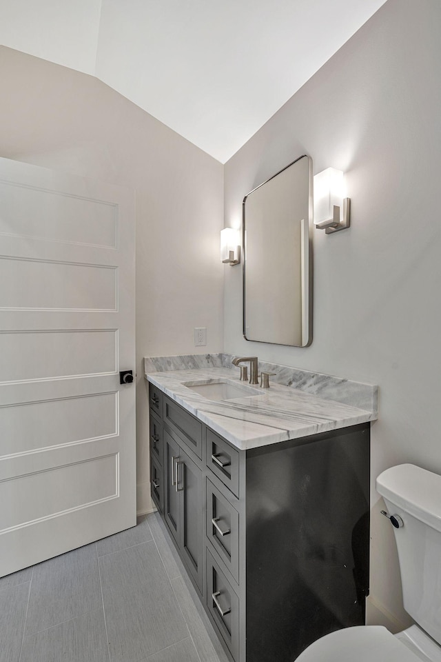 bathroom with vaulted ceiling, vanity, and toilet