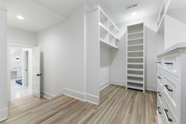 walk in closet with light hardwood / wood-style flooring