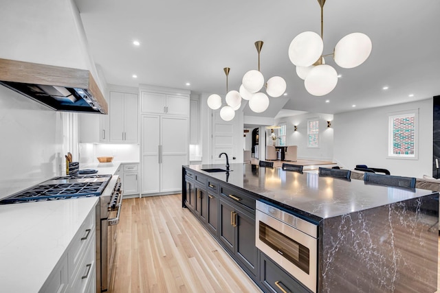 kitchen featuring dark stone countertops, decorative light fixtures, stainless steel appliances, and white cabinets